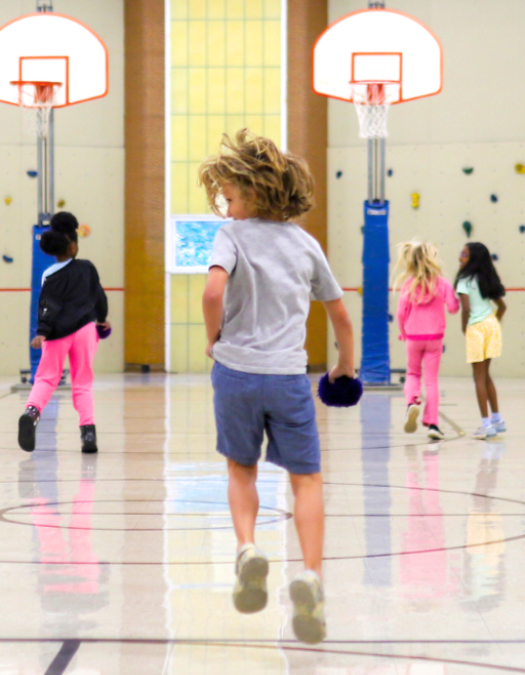 An elementary school Kid playing basketball in gym during recess