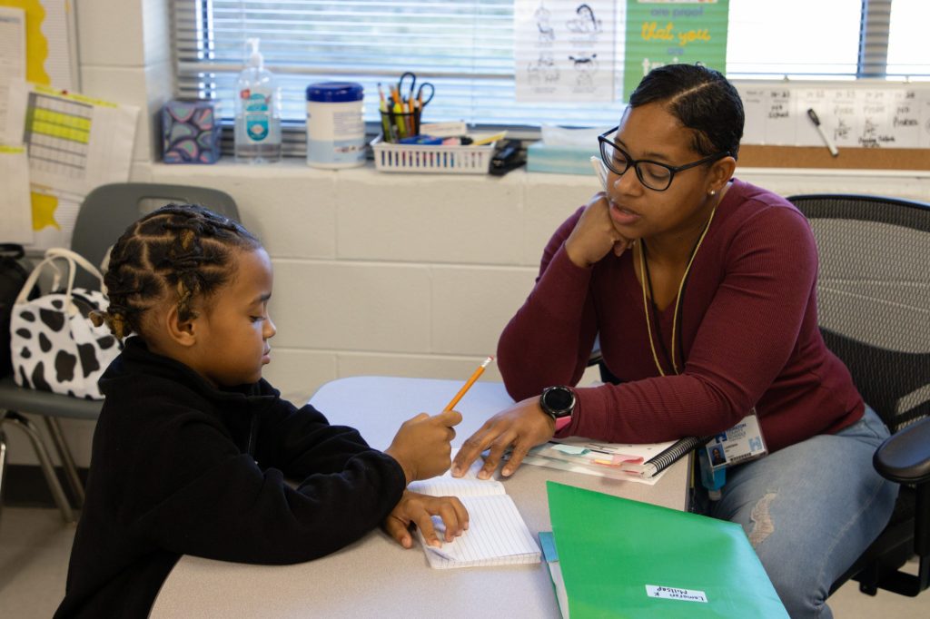 A teacher works with a student