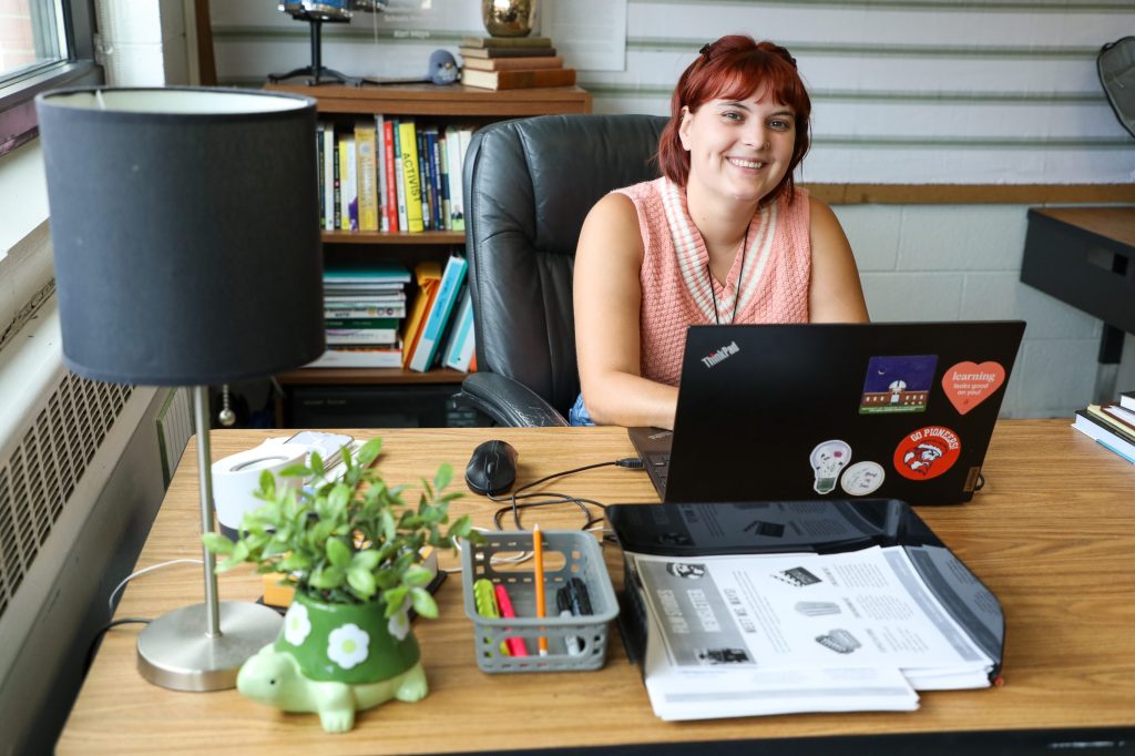 0D5A2031-2 teacher smiling in classroom , sitting behind desk