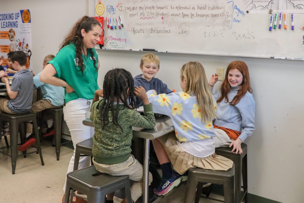 A teacher helps students bake