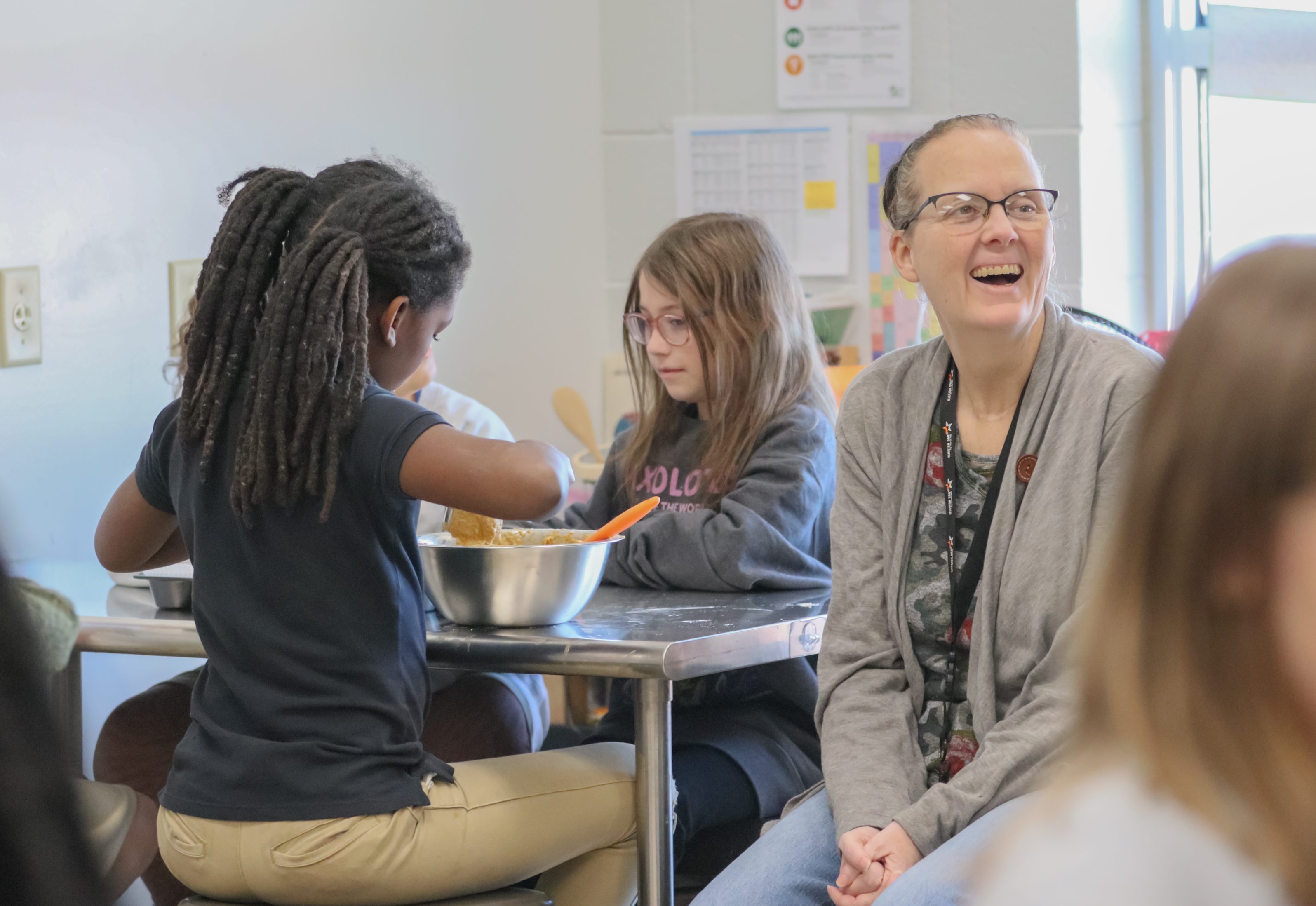 A teacher helps students bake