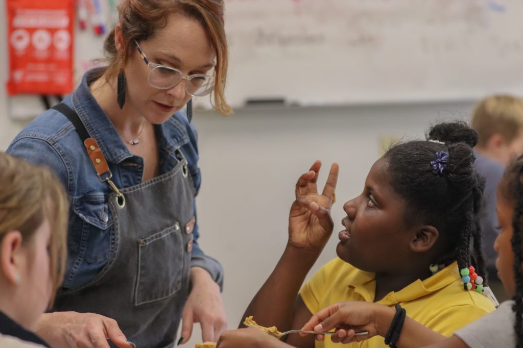 A teacher helps students bake