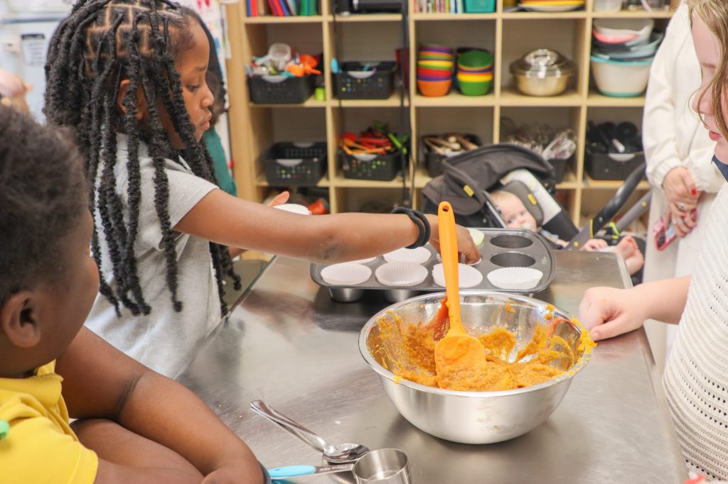 A teacher helps students bake