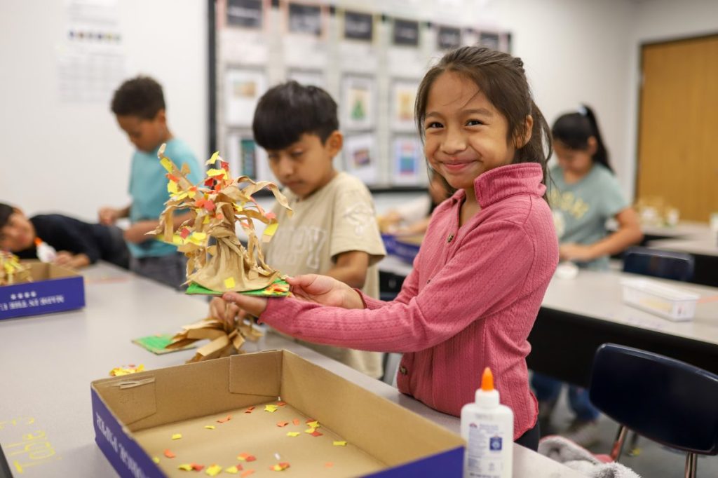 Fall-1 student smiling while doing arts and crafts