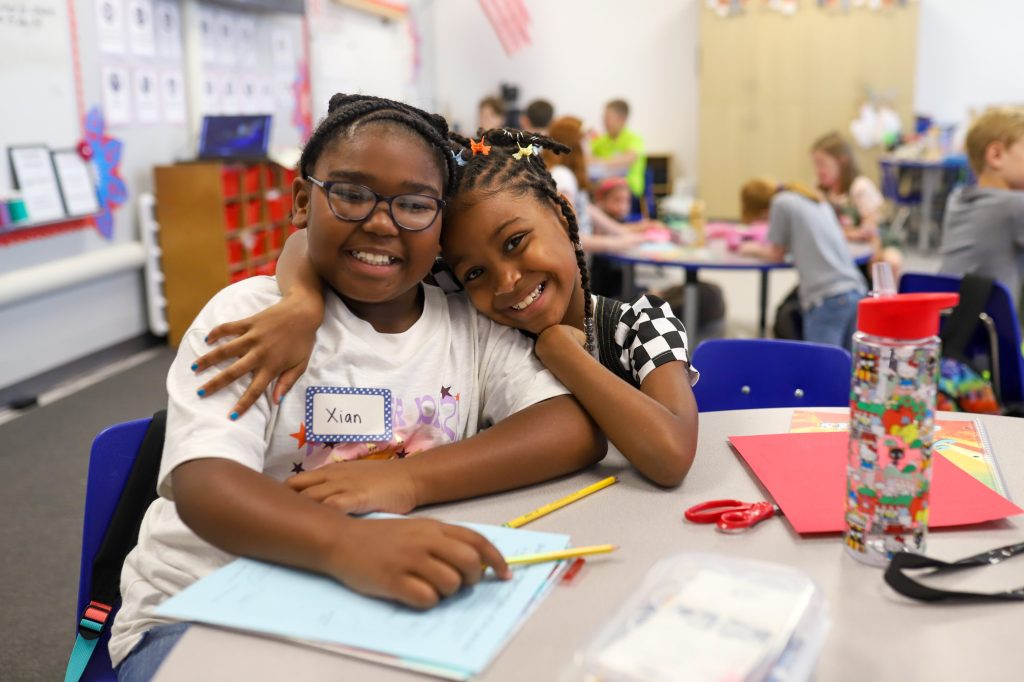 FirstDayEdited-10 two elementary kids smiling at camera in classroom