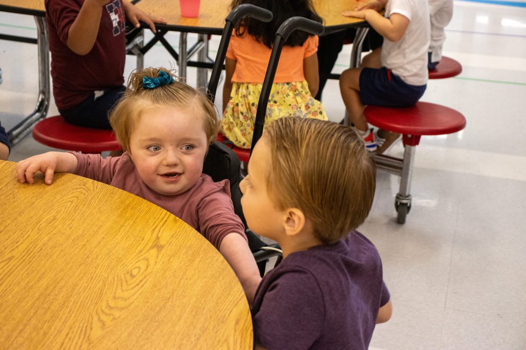 FirstDayEdited-76 child in wheelchair sitting at lunchroom table and interacting with boy