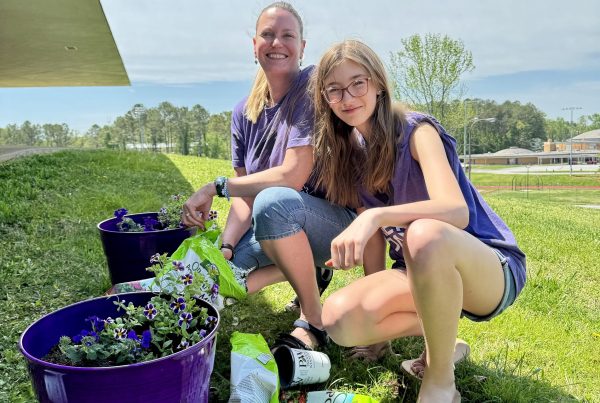 student and adult pose outside while planting