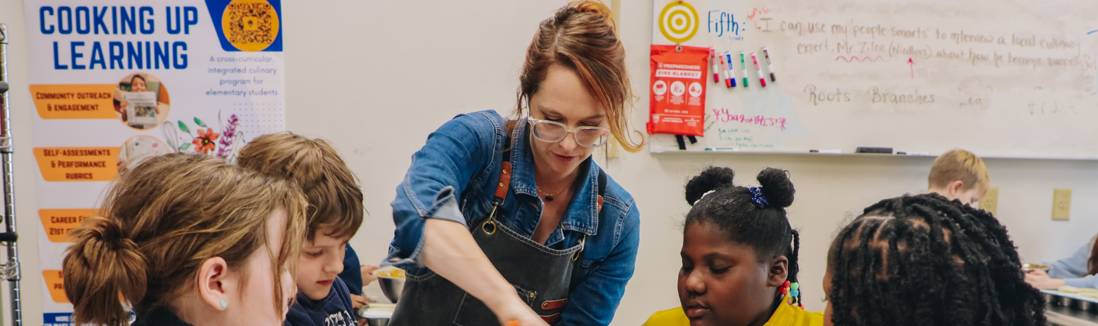 A teacher helps students bake