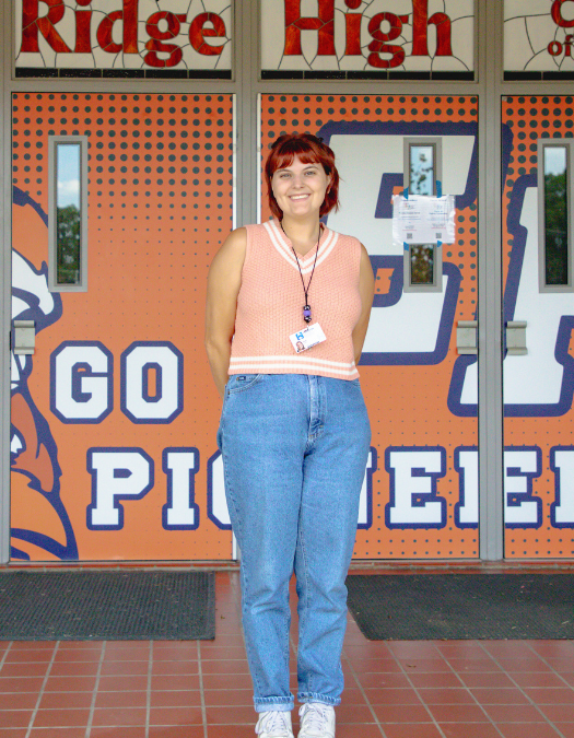 teacher in front of east ridge high front doors