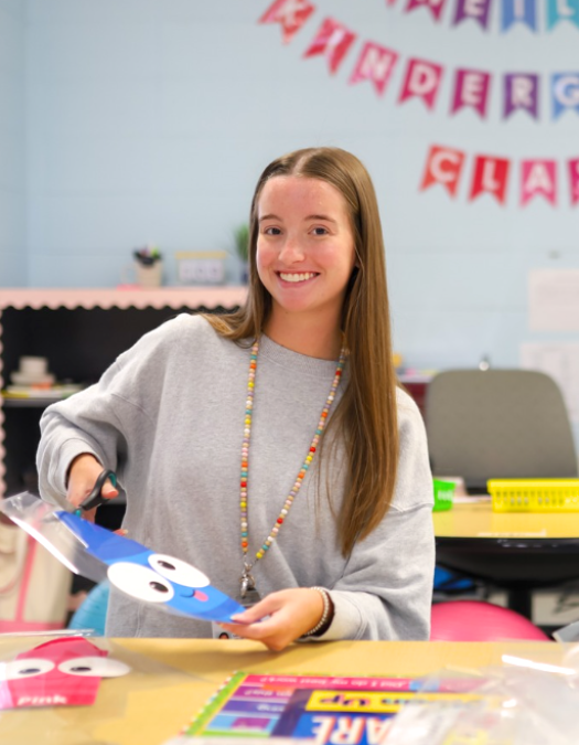 teacher smiling in classroom, cutting up art supplies
