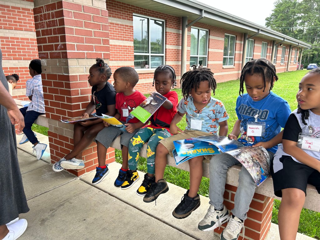 students holding and reading books outside of school